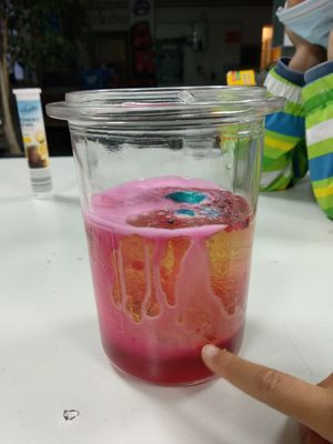 Glas mit bunt gefärbtem Wasser-Ölgemisch - Ansicht von der Seite