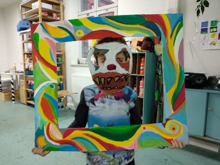 Kind mit selbstgemachter bunter Maske und farbigem Bilderrahmen