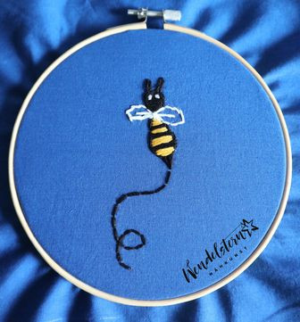 auf blauen Stoff in Webrahmen gesticktes Bienchen