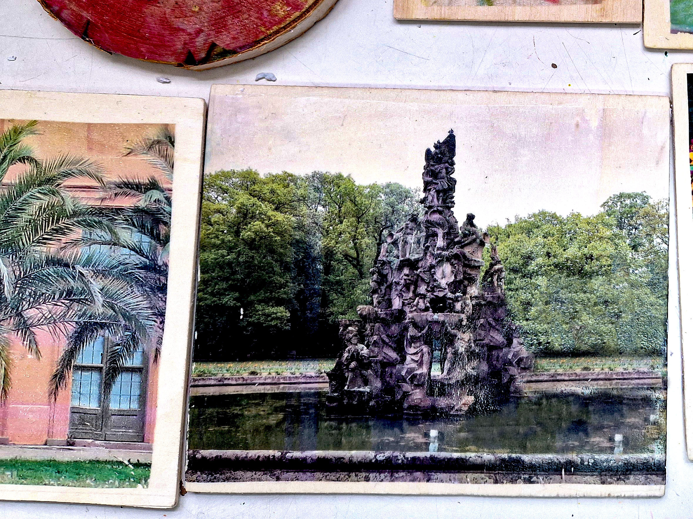 Auf Holzplatten gedruckte Fotografien von einem Brunnen und Palmen