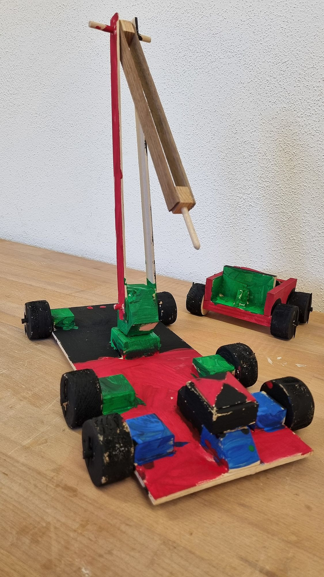 Aus Holz hergestelltes Auto bunt bemalt in Rot, Grün, Blau und Schwarz mit schwenkbarem Kran.
