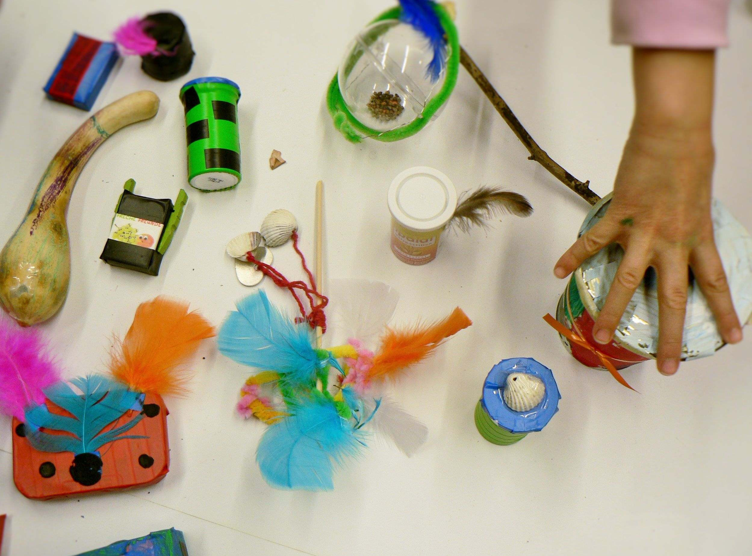 Viele verschiedene bunte Gegenstände verziert und eine Kinderhand die etwas greift.