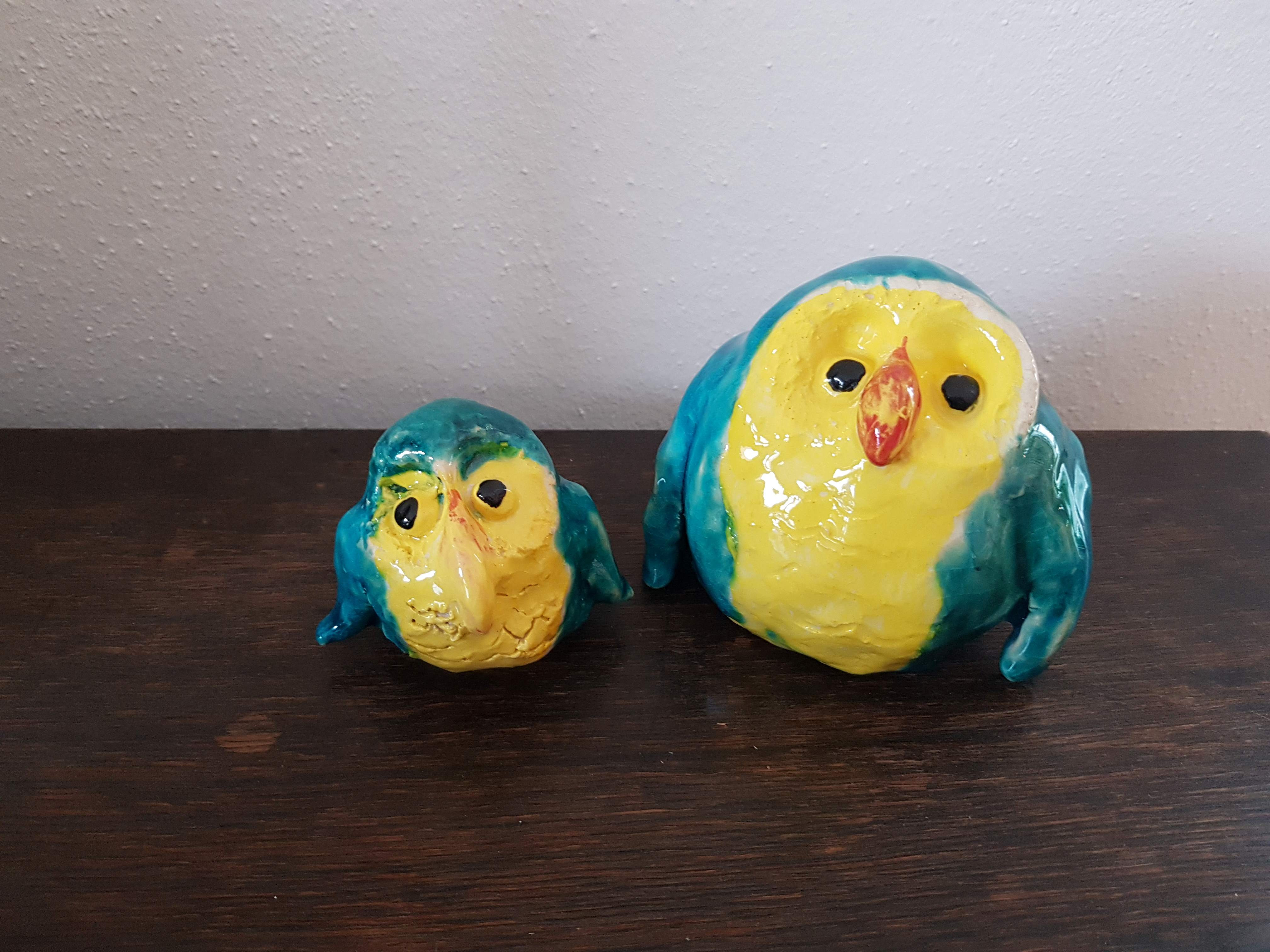 Zwei aus Ton geformte und gelb, blau lasierte Vögelchen.