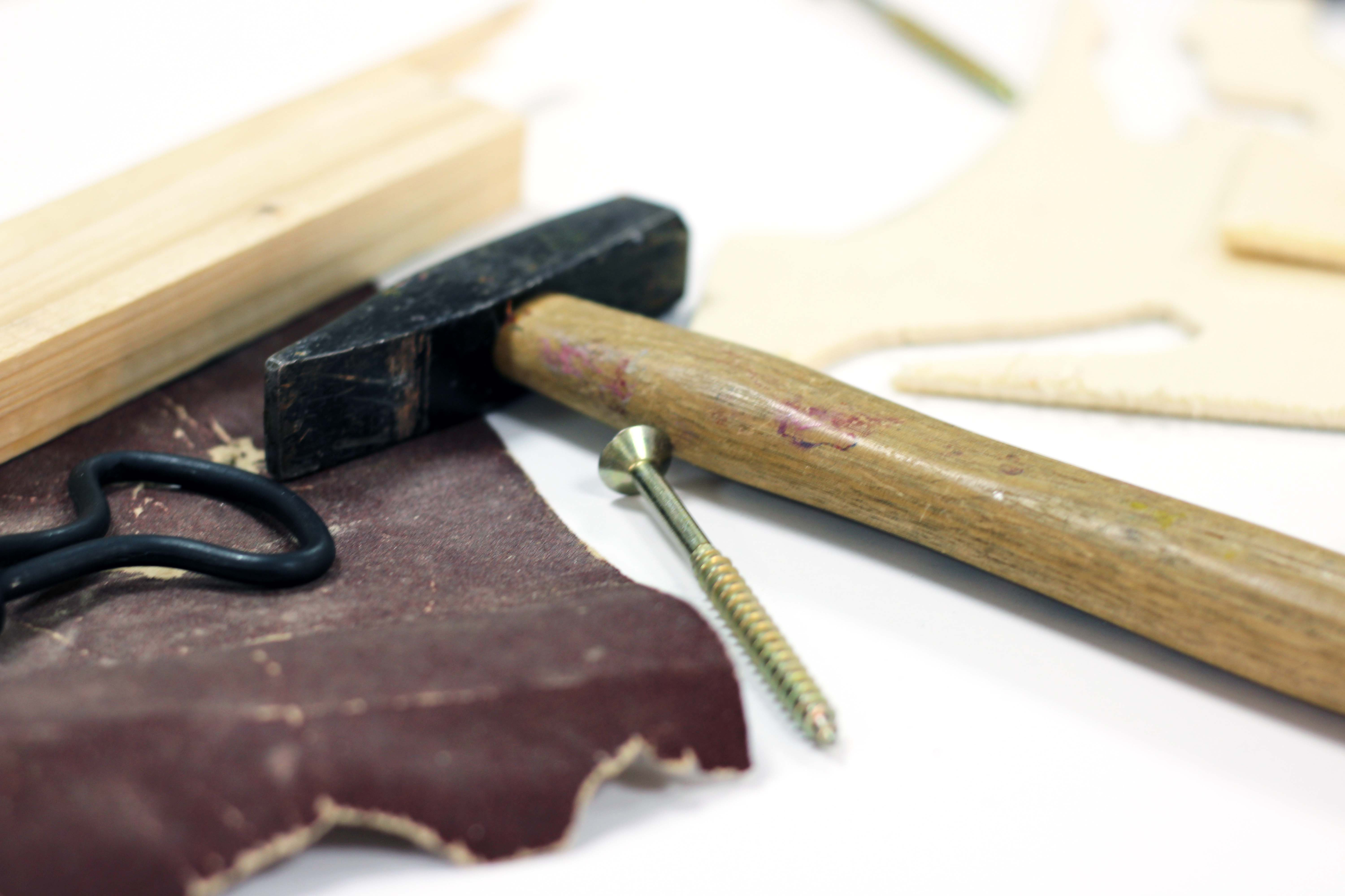 Hammer, Schleifpapier, Holzbohrer, Holz im Hintergrund