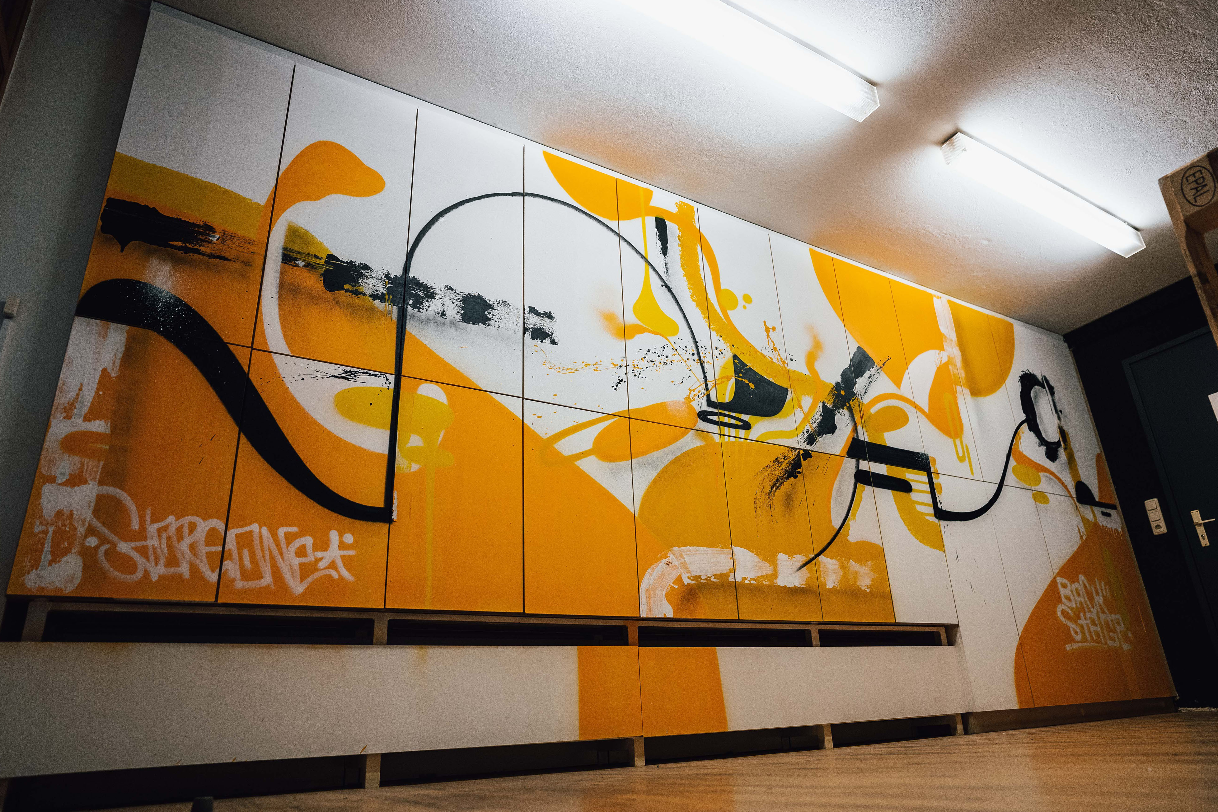 Wand mit abstraktem Graffiti in schwarz, weiß und orange,