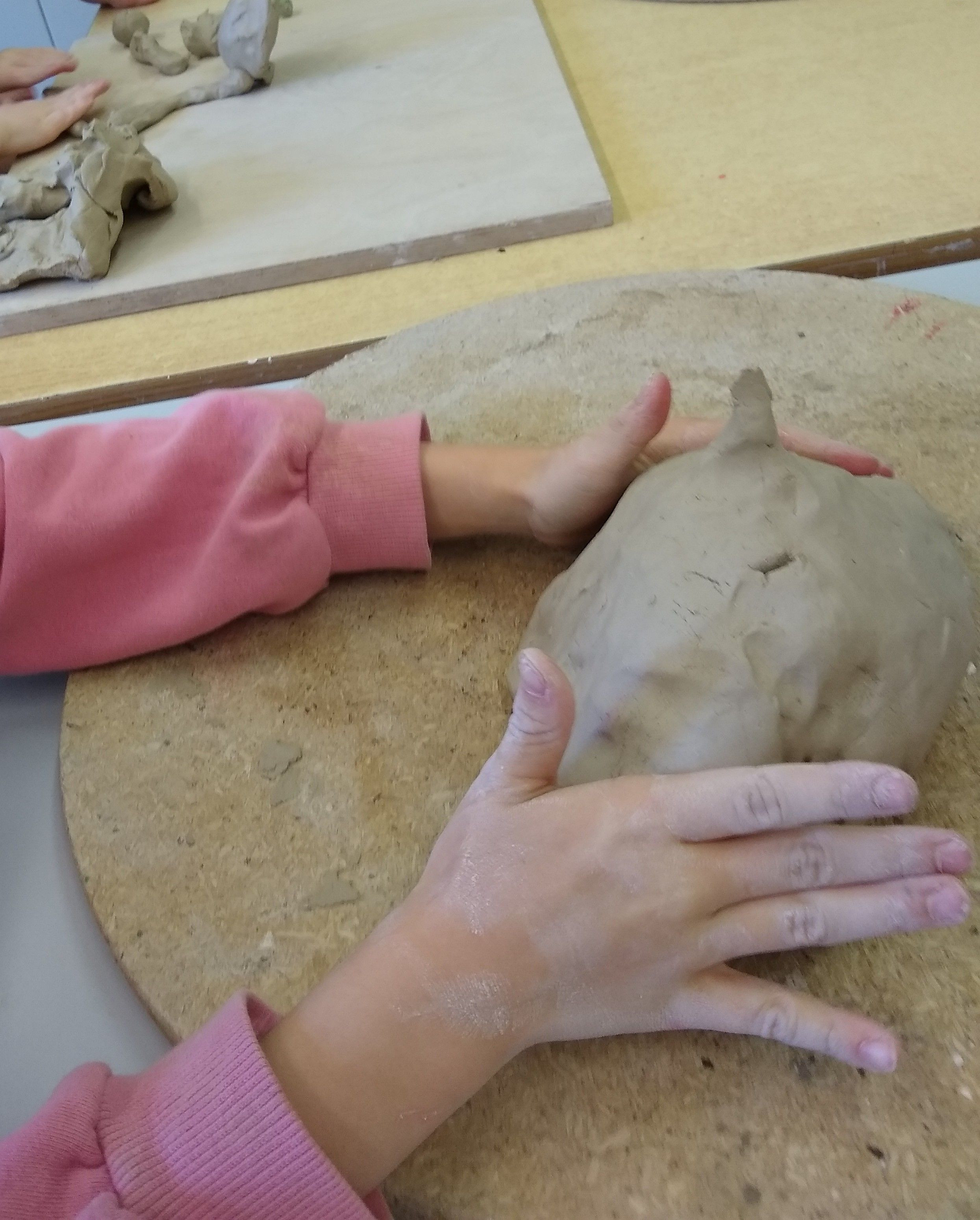 Kinderhände mit einem runden großen Stück Ton