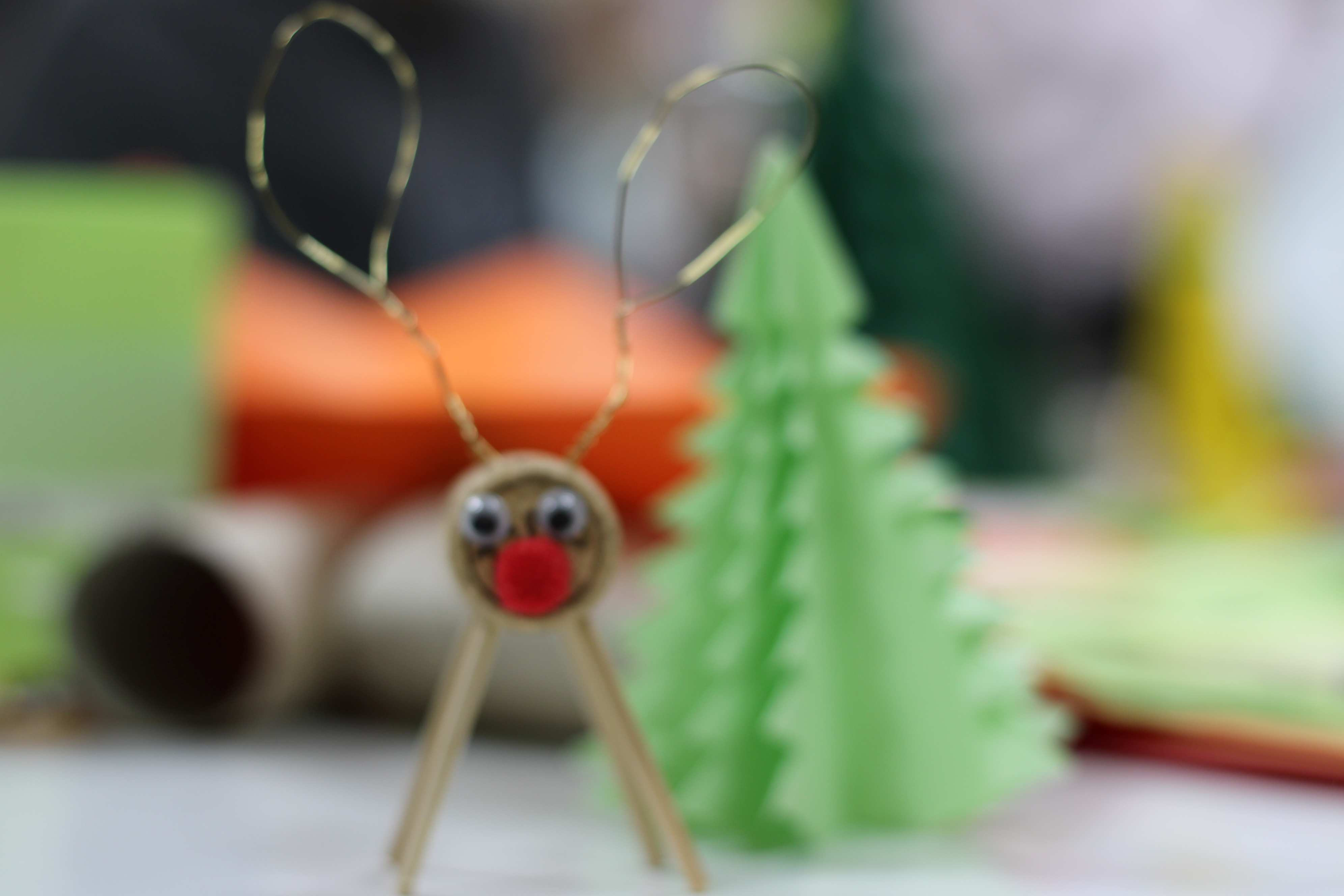 Rentier aus Korken und Draht neben Tannenbaum aus grünem Papier.