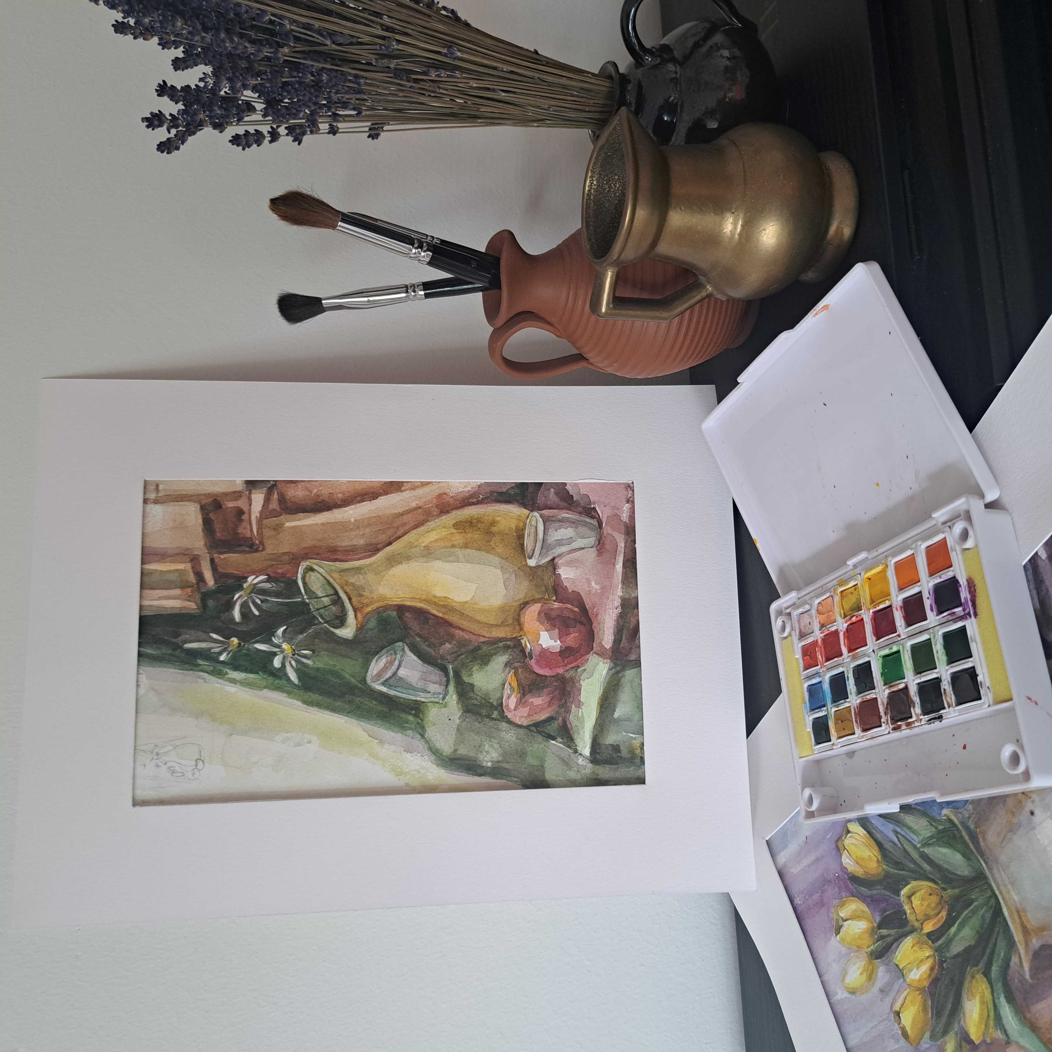 Ein Bild von einer Vase mit Blumen und einem Malkasten.