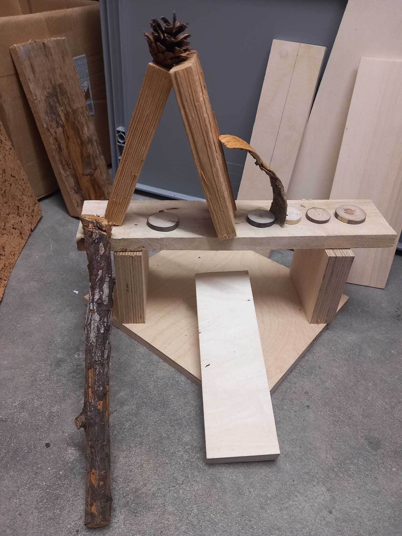 Holzbretter und ein Stock die zu einem Tierhaus zusammengebaut werden soll.