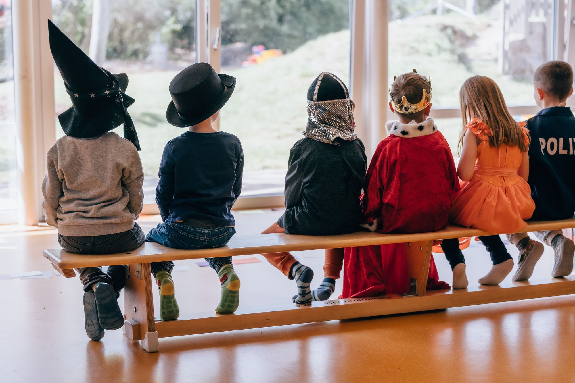 Verkleidete Kinder die auf einer Bank sitzen.