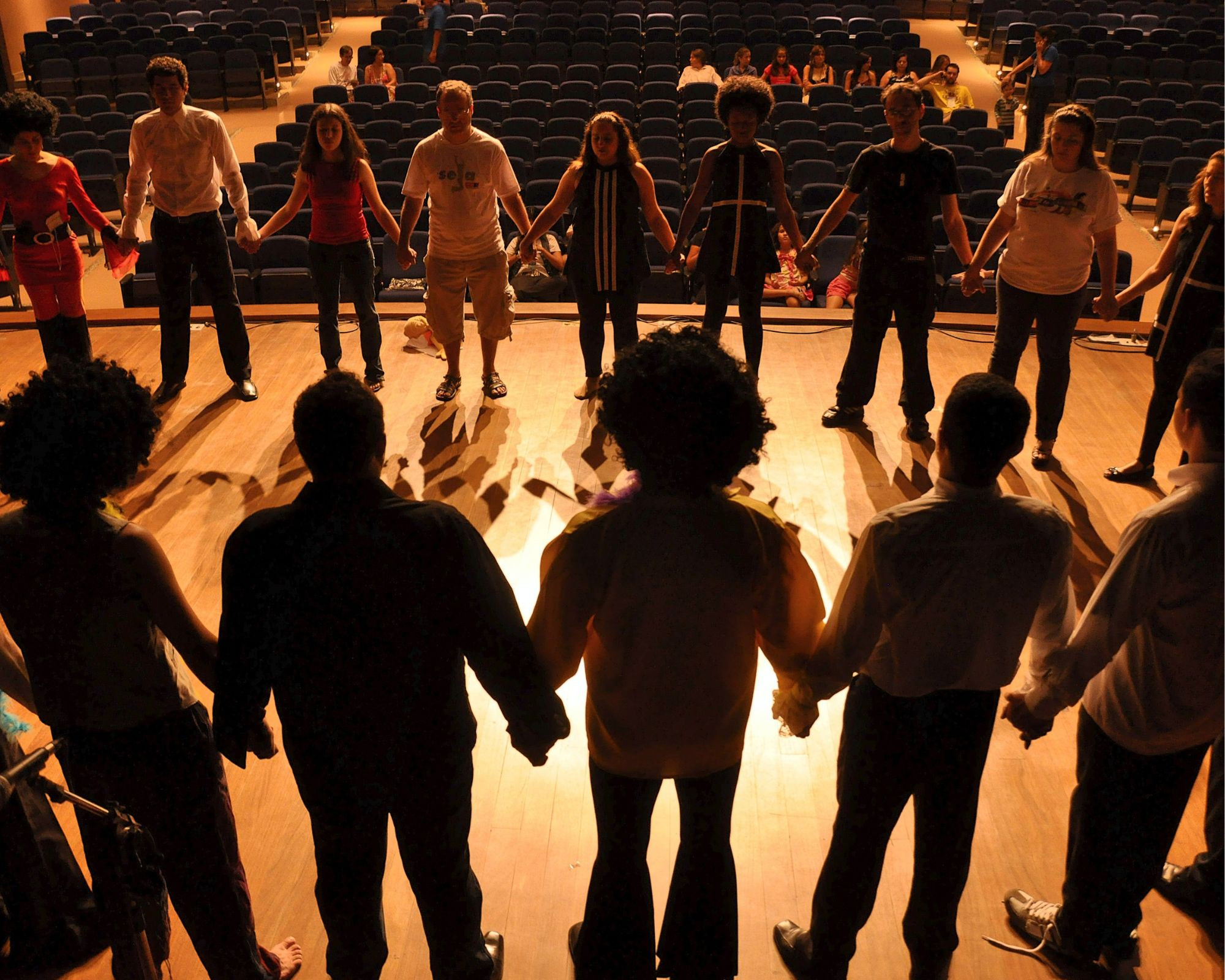 Jugendliche die auf eine Bühne im Kreis stehen und Hände halten