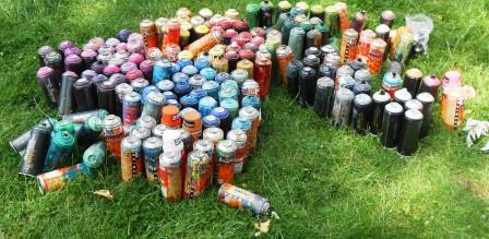 Viele bunte Spraydosen auf einer grünen Wiese.