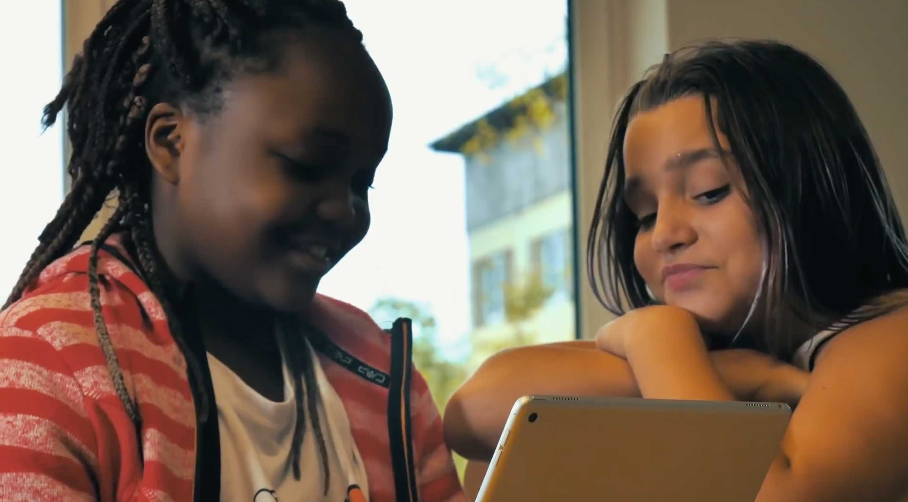Zwei Mädchen schauen, während eines Videodreh, auf den Bildschirm von einem Tablet.