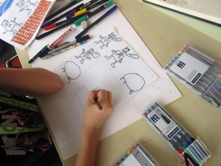 Kind zeichnet mit Finelinern eine Comic-Seite