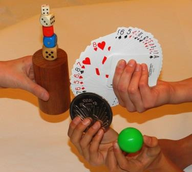 drei Hände zeigen Zaubermaterialien wie Spielkarten, Würfel, Kugel, Münze