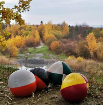 Foto von vier bunten Jonglierbällen vor einem Landschaftshintergrund