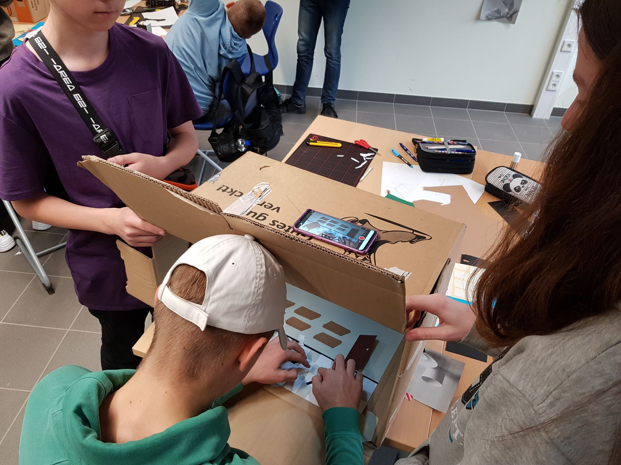 Kursteilnehmer*innen bauen aus Kartons ihr eigenes Trickfilmstudio für die Aufnahmen mit der Smartphonekamera