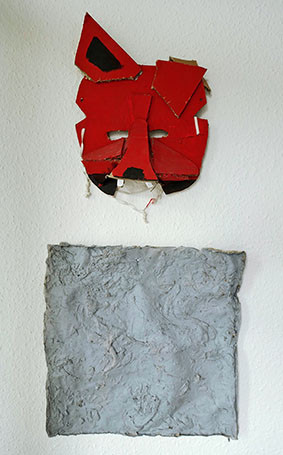 ein Fuchskopf aus Kartonstücken plastisch zusammengesetzt und bemalt; darunter ein graues quadratisches Objekt aus Pappmasché